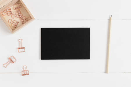 Top view of a black card mockup with workspace accessories on a white table.の写真素材
