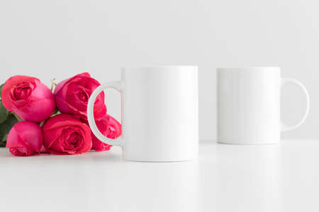 Mug mockup with a bouquet of pink roses on a white table.の写真素材