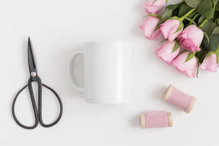 Top view of a mug mockup with a bouquet of pink roses and silk ribbons on a white table.の写真素材