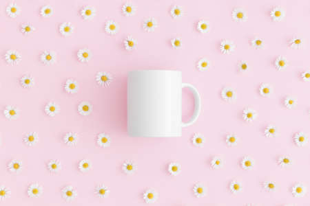 Top view of a white mug mockup with daisy decoration on a pink background.の写真素材