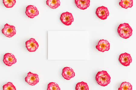Top view of a white card mockup with pink roses decoration on a white background.の写真素材