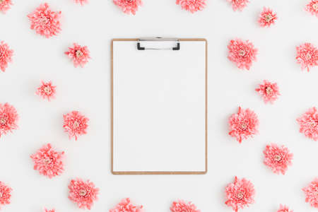 Top view of a wooden clipboard mockup with pink chrysanthemum decoration on a white background.の写真素材