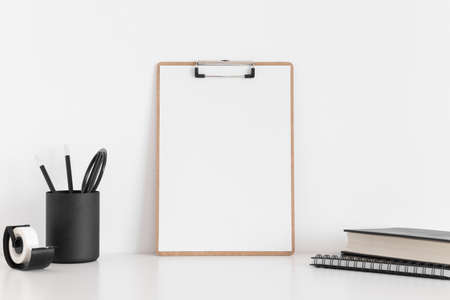 Wooden clipboard mockup with workspace accessories on a white table.の写真素材