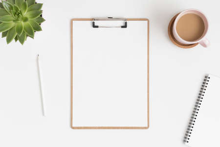 Top view of a wooden clipboard mockup with a succulent plant and workspace accessories on a white table.の写真素材