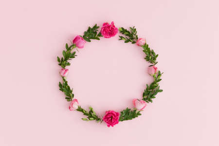 Floral wreath made of pink roses and green branches on a pink background.の写真素材