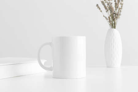 White mug mockup with a lavender in a vase and a book on a white table.の写真素材