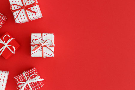 Red and white christmas gifts on a red background. Flat lay with blank copy space.の写真素材