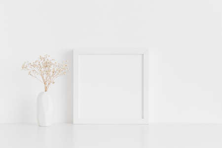 White square frame mockup with a gypsophila in a vase on a white table.の写真素材