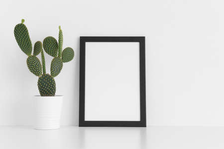 Black frame mockup with a opuntia cactus in a pot on a white table. Portrait orientation.の写真素材