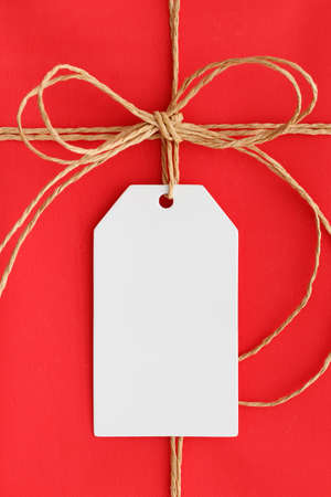 White gift tag mockup on a red christmas gift.の写真素材