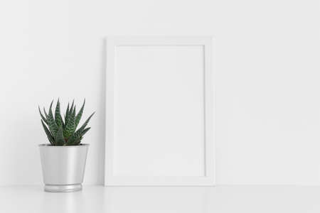 White frame mockup with a cactus in a pot on a white table. Portrait orientation.の写真素材