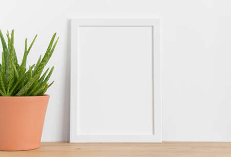 White frame mockup with a aloe vera in a ceramic pot on a wooden table. Portrait orientation.の写真素材