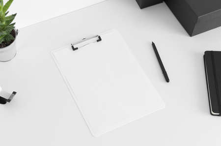 White clipboard mockup wtih workspace accessories on a white table.の写真素材