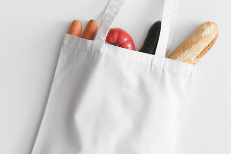 White tote bag mockup with groceries on a white table.