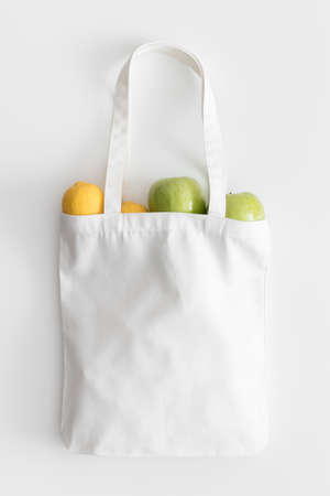 White tote bag mockup with fruit on a white table.の写真素材