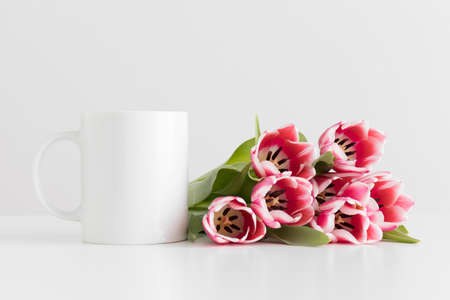 Mug mockup with bouquet of pink tulips on a white table.の写真素材