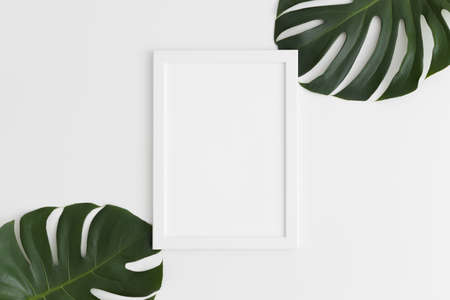 Top view of a white frame mockup with monstera leaf decoration. Portrait orientation.の写真素材