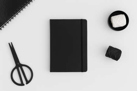 Black notebook mockup with workspace accessories on a white table.の写真素材