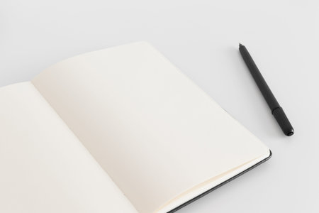 Open notebook mockup with a pen on a white table.