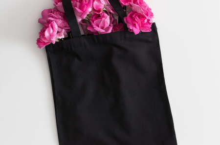 Black tote bag mockup with a bouquet of a roses on a white table.の写真素材