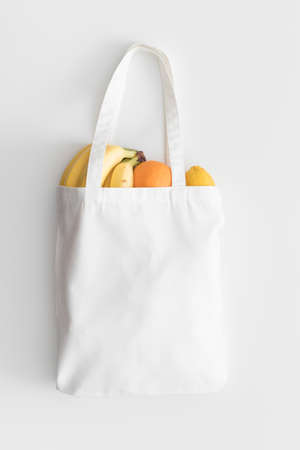 White tote bag mockup with fruit on a white table.の写真素材