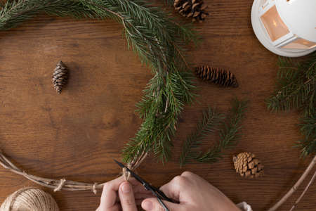 Making a christmas wreath with firs and cones on a wooden table.の写真素材