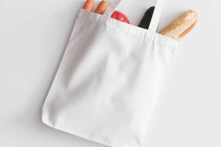 White tote bag mockup with groceries on a white table.の写真素材