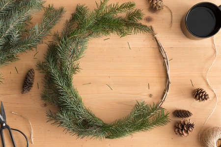 Making a christmas wreath with firs and cones on a wooden table.の写真素材