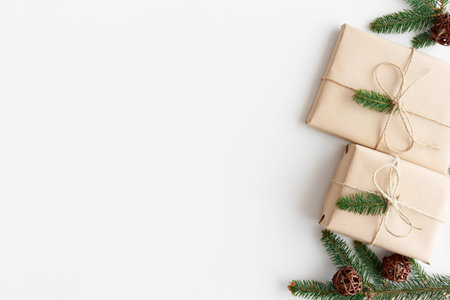Christmas gifts with pine leaves and twine on a white table. Flat lay with blank copy space.