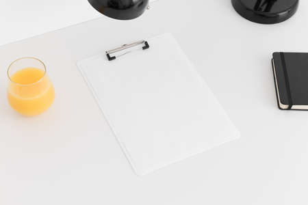 White clipboard mockup wtih workspace accessories on a white table.の写真素材