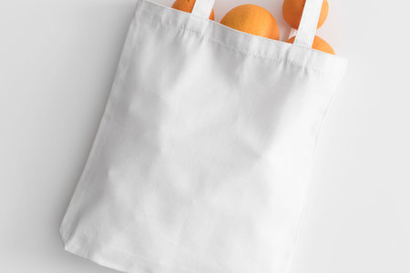 White tote bag mockup with oranges on a white table.