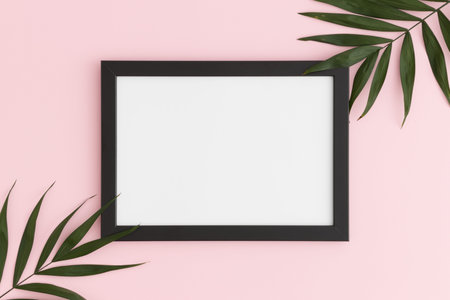 Top view of a black frame mockup with palm leaf decoration on a pink background. Landscape...