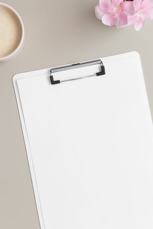 White clipboard mockup with a cup of coffee and oleander on a beige table.
