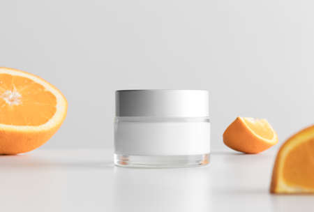 Cream cosmetic bottle mockup with oranges on a white table.の写真素材