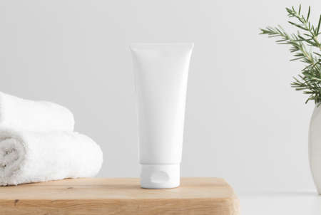 White tube cream mockup with towels and a rosemary on a wooden table.の写真素材
