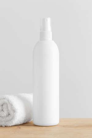 White cosmetic bottle spray mockup with a towel on a wooden table.の写真素材