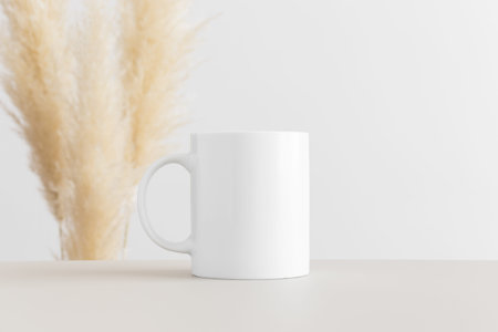 White mug mockup on a beige table with pampas decoration.
