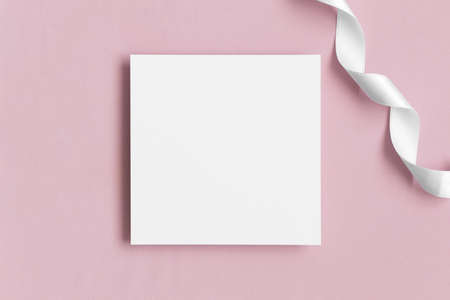 Invitation square card mockup with a satin tape on a soft pink textile.の写真素材