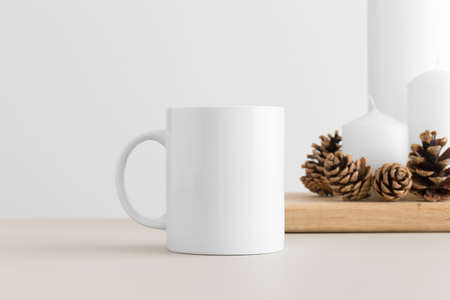 White mug mockup with candles on a table. Christmas decorationの写真素材
