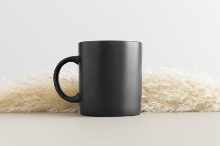 Black mug mockup with a pampas on a beige table.の写真素材