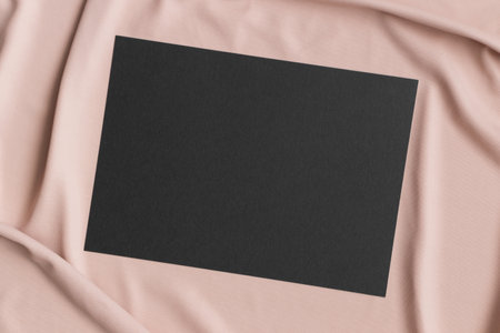 Invitation black card mockup on a beige textile. 5x7 ratio, similar to A6, A5.の写真素材