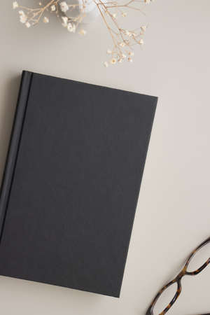 Black book mockup with a dried gypsophila decoration on a beige table.の写真素材