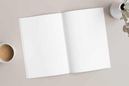 Open magazine mockup with a cup of coffee and a eucalyptus on the beige table.の写真素材