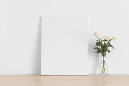 White canvas mockup with a bouquet of a pink roses on the wooden table.の写真素材