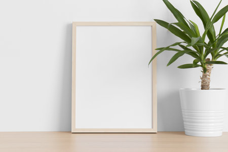 Wooden frame mockup with a yucca plant on the wooden table.