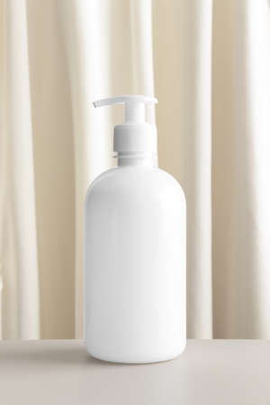 White cosmetic liquid soap dispenser bottle mockup with a yellow textile.の写真素材