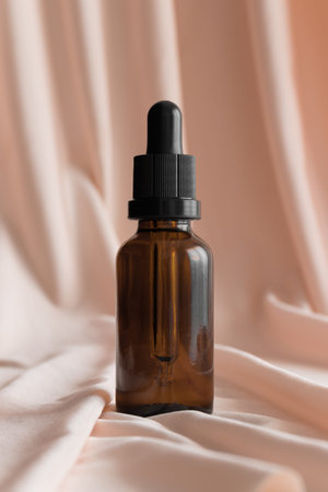 Dropper bottle mockup on the soft pink textile.