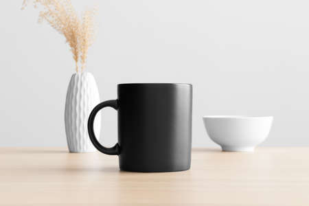 Black mug mockup with a dry flower decoration on the wooden table.の写真素材
