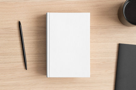 White book mockup with a cup of coffee and workspace accessories on the wooden table.の写真素材