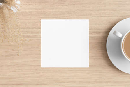 Square invitation card mockup with a dry flower the wooden table.の写真素材